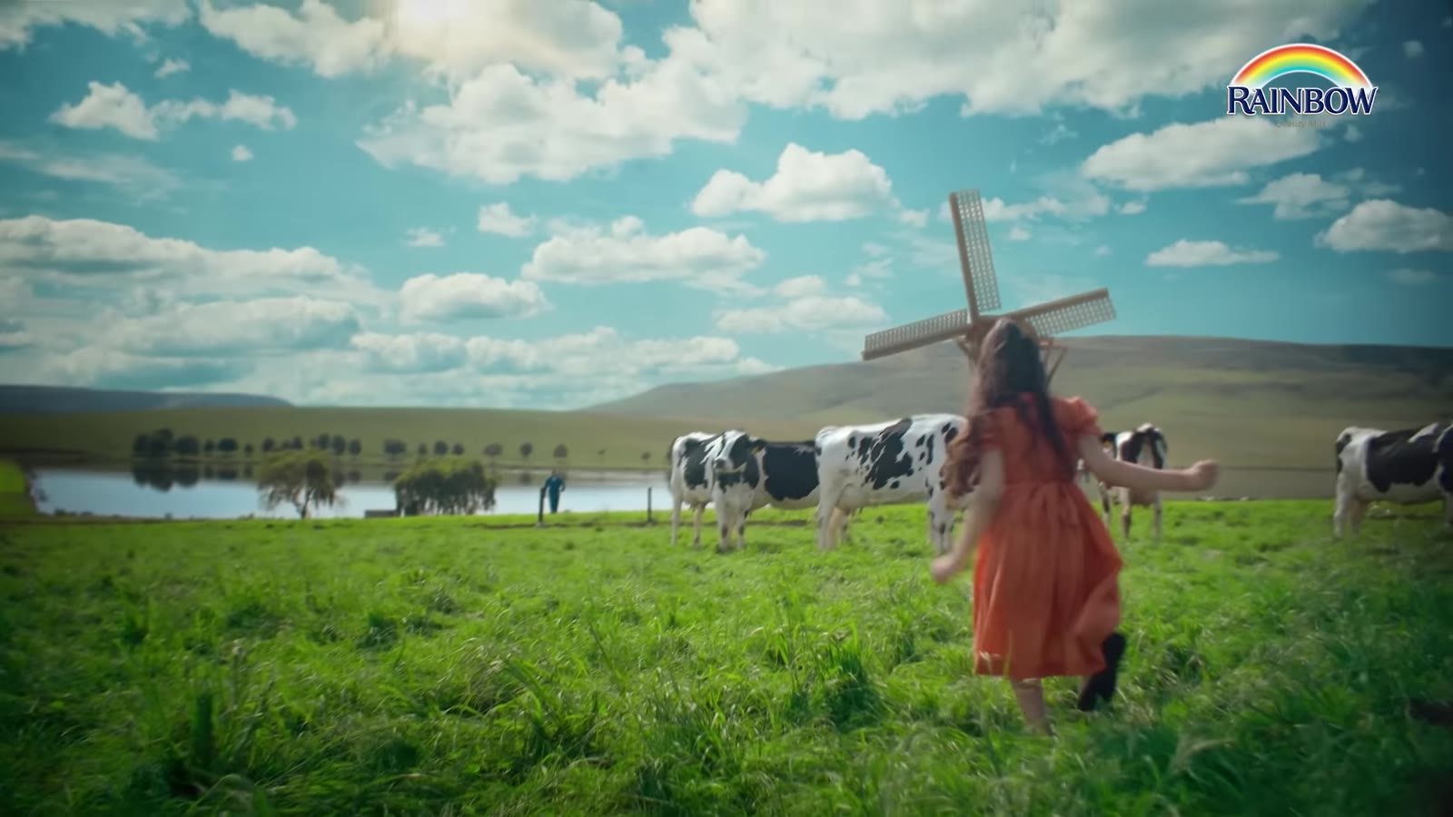 Rainbow Milk jingle — a girl running through a green meadow with cows and a windmill